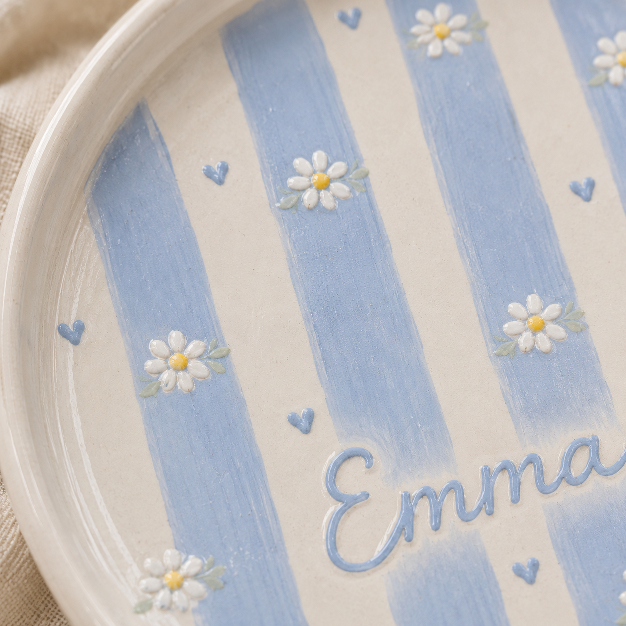 Close up of blue striped ceramic trinket dish with daisy details and Emma name