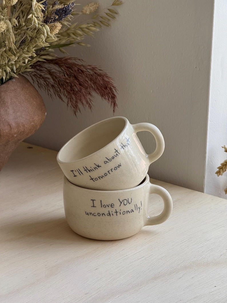 Two personalized ceramic mugs beside dried flowers